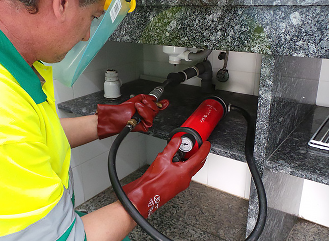 Técnico de Conlima realizando un desatasco en fregadero doméstico con herramienta profesional, servicio especializado en cocina y baños.